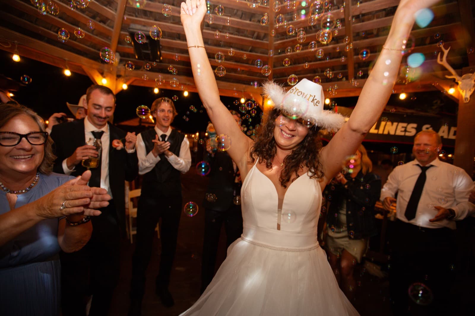 Bride celebrating on dance floor with cowboy hat and bubbles