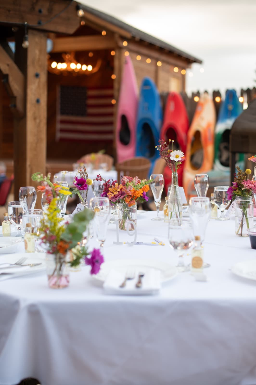 Reception table with wildflower centerpieces and colorful kayaks as backdrop